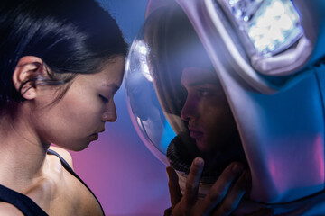 Astronaut couple with woman in casual clothes dressing man standing in helmet and spacesuit