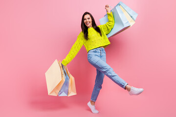 Photo of cheerful glad lady wear yellow denim clothes carry bags rejoice special seasonal offer isolated on pink color background