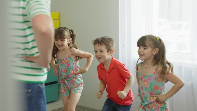 Two tall girls and a boy repeat the movements of the teacher. A fun, moving activity for children between classes. High quality 4k footage
