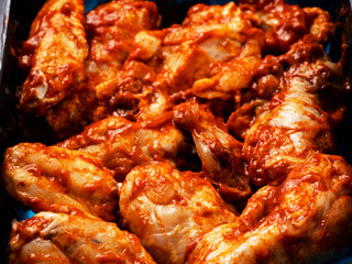Raw uncooked marinated chicken wings in black plastic tray. High quality poultry product with delicate rich flavor. Food supply chain.