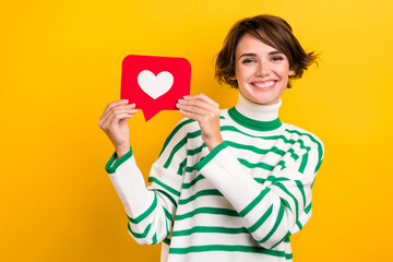 Photo of positive sweet lady wear striped pullover smiling rising heart like card isolated yellow color background