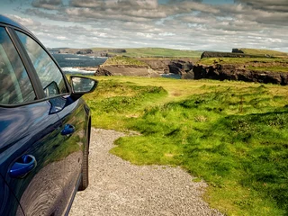 Fototapete Atlantikstraße Dark color car parked off road, Stunning nature scene in the background with cliffs and low cloudy sky, sunny day. Kilkee area, Ireland. Travel, tourism and sightseeing concept. Irish landscape.