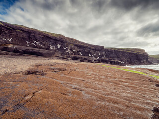 Powerful waves hit rough stone coast with cliffs and ocean scene. Ireland, Kilkee area. Travel, tourism and sightseeing concept. Irish landscape and nature scene. Nobody. Dramatic nature view.