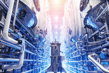 Obraz premium Tanks in modern beer factory, Pipes stainless steel brewing equipment, sun light. Brewery food industrial production concept