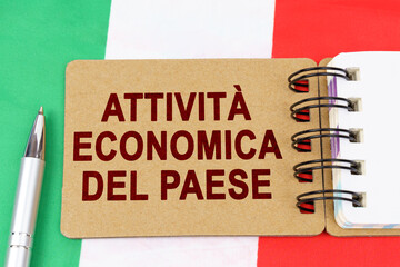 On the flag of Italy lies a pen and a notebook with the inscription - economic activity of the country