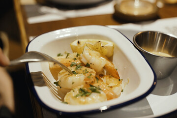 A dish of freshly prepared grilled shrimp with sauce and lemon in a white plate.