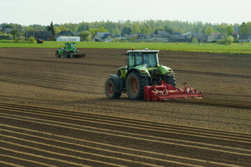 Obraz premium Tractors plow the field and prepare the soil for sowing.