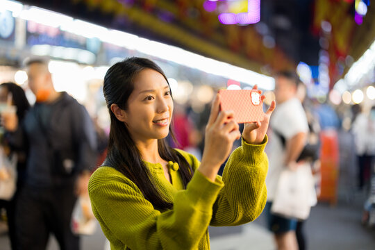 Woman use cellphone to take photo in street market at Taiwan