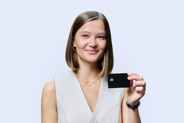 Young woman bank employee showing credit card, on white background