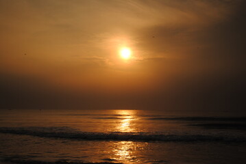 Bright sun coming out on a early morning displaying a golden cloth on the sea captured with selective focus in Chennai