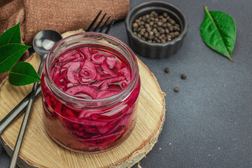 Jar with tasty pickled onions on black table. Cutlery, served meal ready to eat, trendy stand