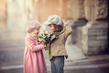 Girl and boy with flower bouquet on the city street talking and laughing in spring