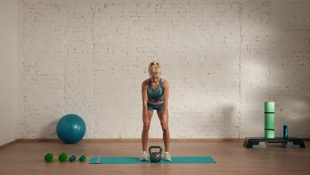 Healthcare and wellness advertisement concept. Athletic woman fitness coach doing explaining back bends with kettlebell.