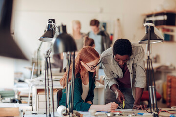 Young diverse pair of architects sketching building plans in the office
