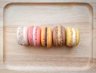 Top view of homemade colorful macarons on a wooden tray