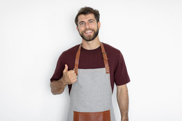 Happy man barista or waiter wearing apron working in coffee shop showing thumb up like gesture isolated on light background. Small business startup
