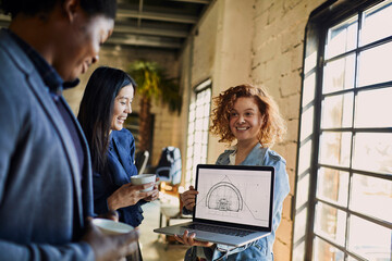 Obraz premium Young Caucasian female designer showing her building plans progress to her colleagues in a startup company office