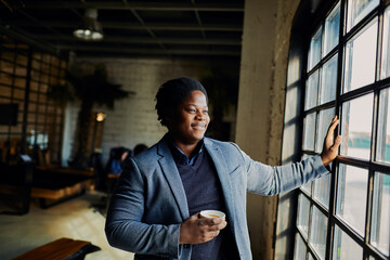 Young businessman looking out the window on a coffee break in the office