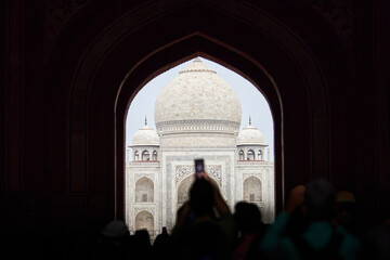 Archway of main gateway in Taj Mahal entrance with tourists silhouettes, view to Taj Mahal marble...