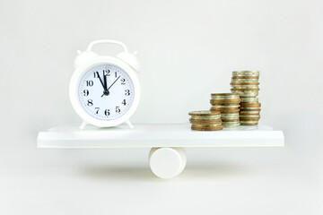 Balance Between Time and money concept. White sand clock and dollar bagson a balance scale in equal position on white background.