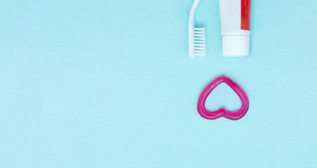 Closeup of a toothpaste, toothbrush and toothpaste heart on blurred blue background. Orthodontic dental theme.