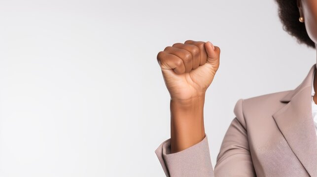 A black woman raising her fist in a business suit, strong and empowered workers