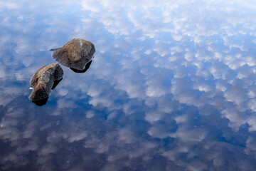 reflection of the sky and rock in the water