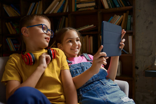 Charming little school children watching video together using mobile tablet