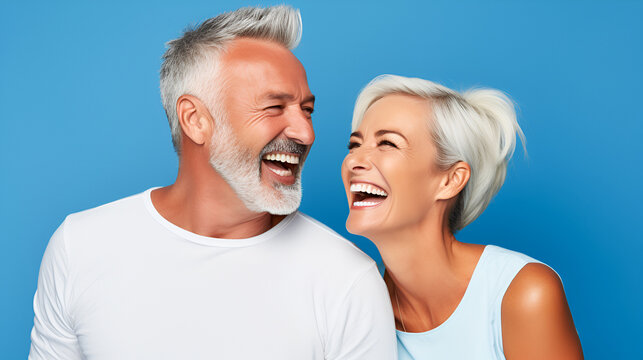 portrait of smiling elderly gray-haired couple happy pensioners man and woman with white perfect teeth isolated on blue background with copy space. Dental care. Dental prosthetics. Dentistry concept.
