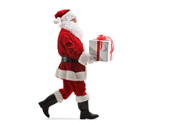 Full length profile shot of santa claus walking and carrying a present box