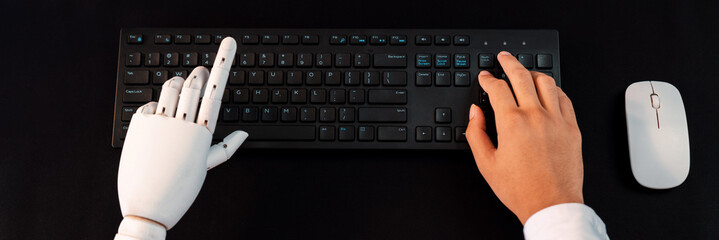 Top view robot and human hand typing keyboard. Artificial Intelligence or generative AI utilized in...