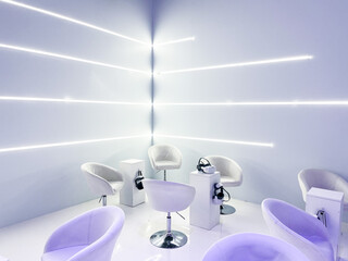 white room with LED lights on the walls, armchairs and 3D viewers placed on the tables