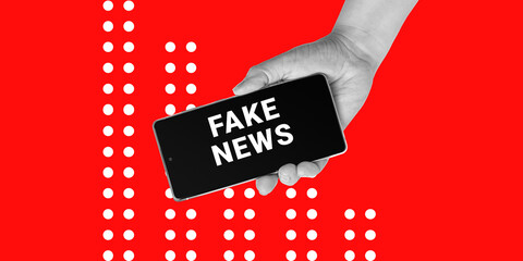 Deception, Politics, Propaganda. Hand holds a smartphone with inscription FAKE NEWS on red...