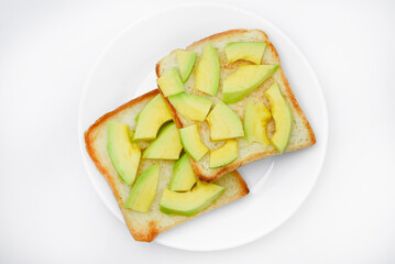 Fried toast with slices of green avocado. A delicious lunch of bread and ripe avocado.