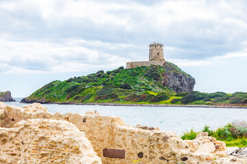 Ruins of Roman civilization, Nora, Sardinia, Italy and lighthouse in the background - obrazy, fototapety, plakaty