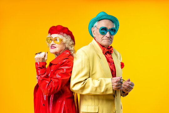 Beautiful senior old couple wearing fancy party clothes acting in studio on a colored background. Conceptual image about third age and seniority, old people feeling young inside.