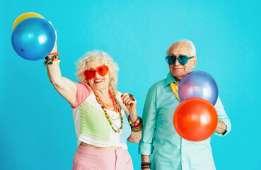 Beautiful senior old couple wearing fancy party clothes acting in studio on a colored background....