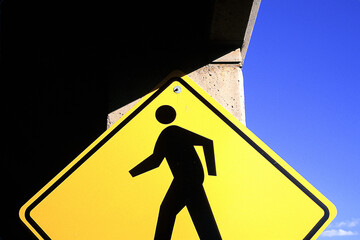 Low angle view of yellow pedestrian crossing sign against blue sky