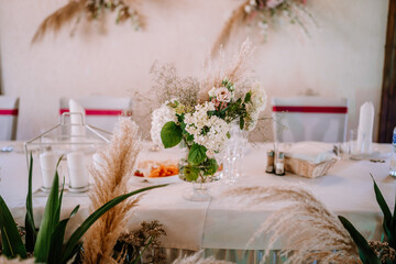 Wedding table set up in boho style with pampas grass and greenery, soft focus