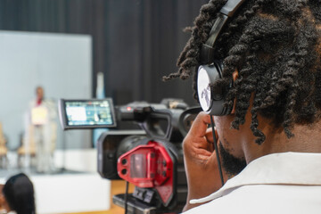 african cameraman with dreadlocks with camera filming an event indoors