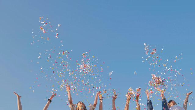 Tossing colorful paper confetti from the hands of young people.