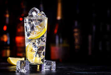 Vodka tonic transparent cocktail drink with cold vodka, lemon juice, tonic and ice cubes. Black...