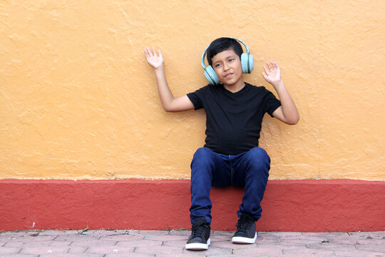 Brown Latino 9 year old boy with anti noise headphones for children with asperger syndrome, autism spectrum disorder, ADHD and children with sensitivity to loud noises