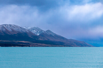 Photograph of Lake Pukaki early in the morning on a cloudy day with snow-capped mountains in the background on the South Island of New Zealand