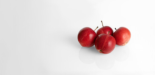 Red apples on a white background with a mirror surface.