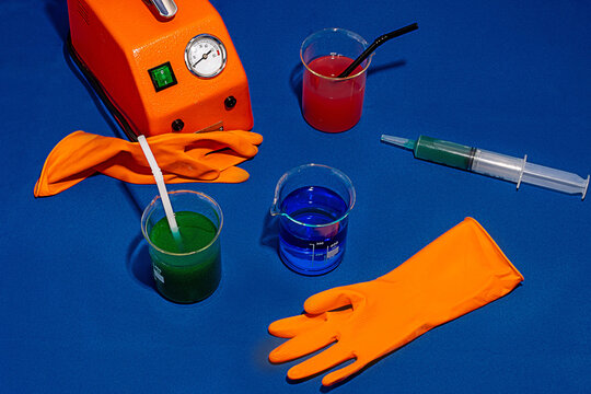 Chemical drinks on blue table near machine glove and syringe