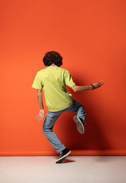 Unrecognizable man in dark hair dancing near red wall
