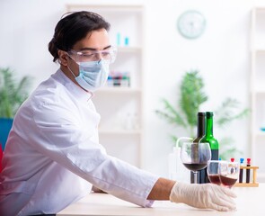 Male chemist examining wine samples at lab