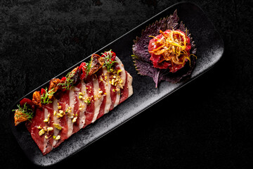 Smoked duck breast fillet sliced and tartare beef on plate in restaurant.