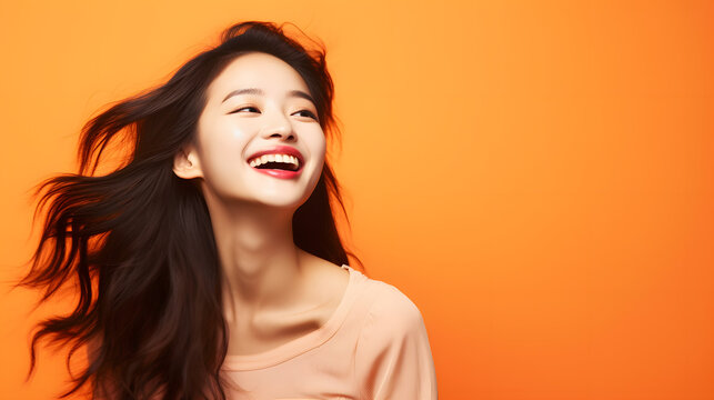 happy young japanese, asian woman against orange background